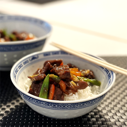 Stir-fried beef with bell pepper and sugar snap peas served over rice